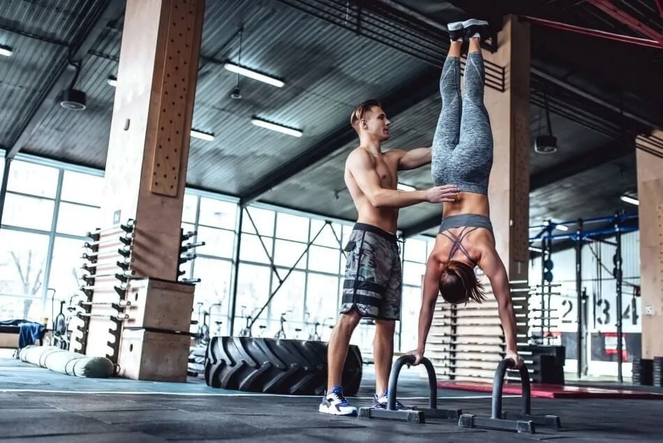 Woman performing handstand with spotter